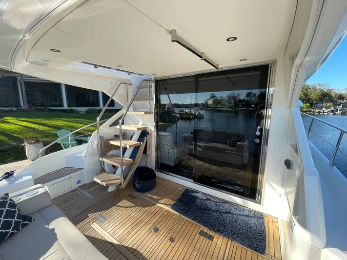  Yacht Photos Pics 2017 Fairline Squadron 48 yacht deck with wooden flooring and glass door, docked by water.