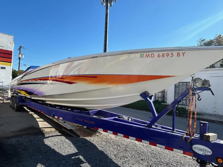  Yacht Photos Pics 2001 Cigarette 46 Rough Rider boat on trailer, vibrant orange and purple design, clear blue sky.