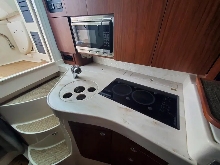 Rising Sun Yacht Photos Pics 2018 Grady-White Express 330 boat kitchen with stove, microwave, and wooden cabinetry.