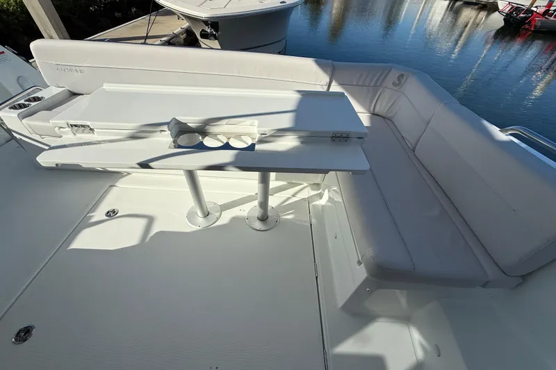  Yacht Photos Pics 2026 Beneteau Antares 12 boat deck with white seating and table, docked by water.