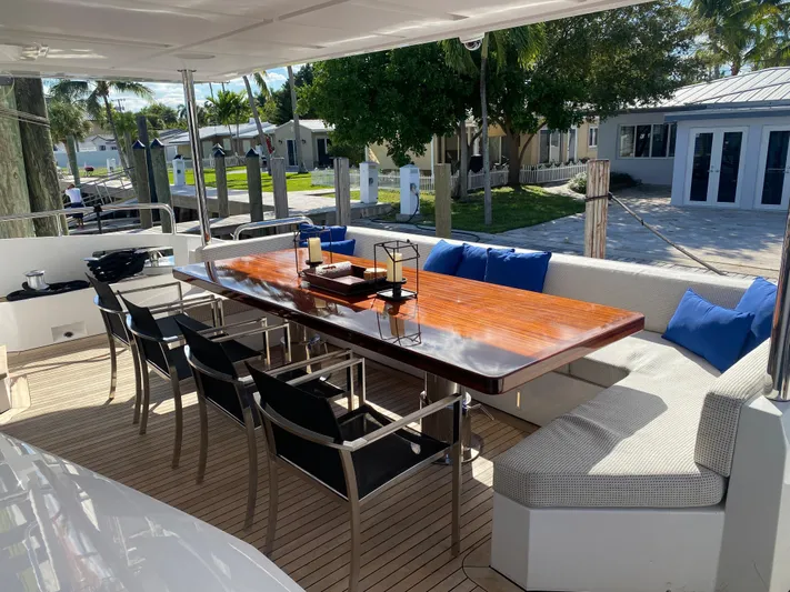 La Tache Yacht Photos Pics Outdoor dining area on 2014 Azimut 100 Grande yacht with wooden table and cushioned seating.