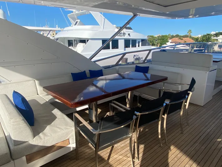 La Tache Yacht Photos Pics Outdoor dining area on 2014 Azimut 100 Grande yacht with wooden table and cushioned seating.
