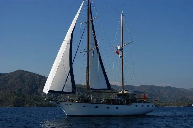Sailing yacht on calm sea with mountainous backdrop, custom model from 2006.
