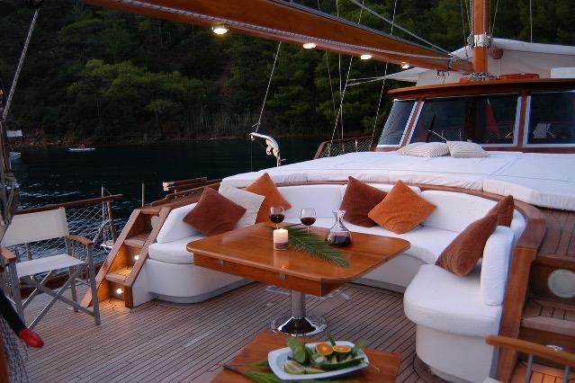 Luxurious yacht deck with cozy seating, wine glasses, and scenic waterfront view.