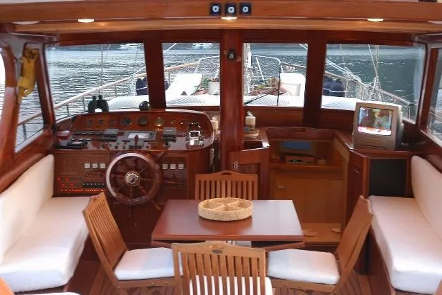 Luxurious custom yacht interior with wooden helm, seating, and dining area, built in 2006.