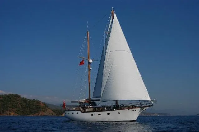 Custom 2006 sailboat with white sails on calm blue sea, clear sky background.