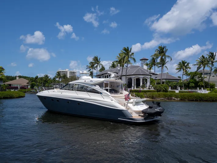 Road Runner Yacht Photos Pics 2008 Princess V53 yacht cruising near waterfront homes and palm trees under a clear blue sky.