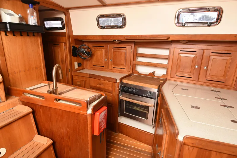 Makasi Yacht Photos Pics Wooden interior of 2008 Tartan 4100 yacht kitchen with sink, stove, and cabinets.