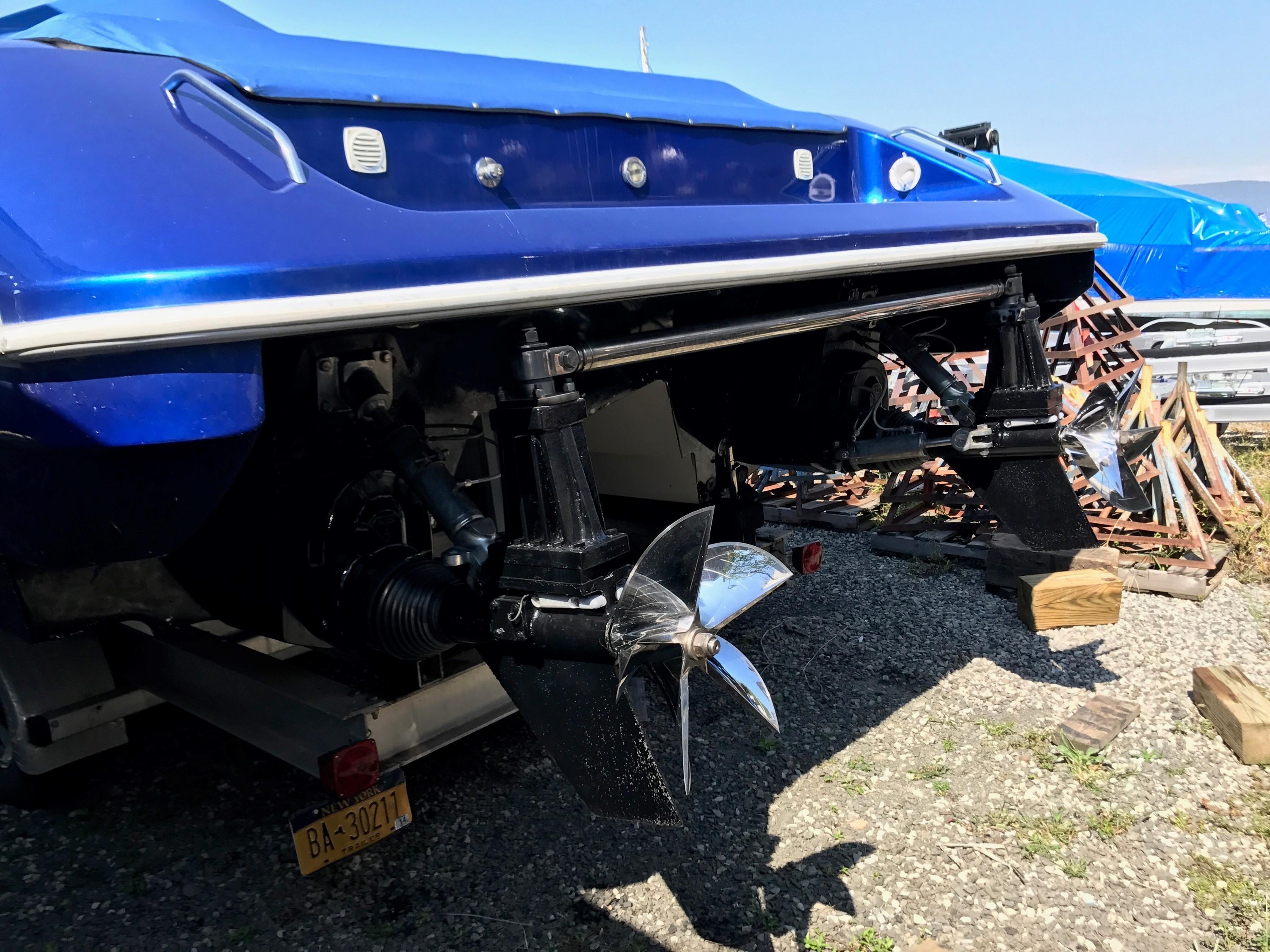 2002 Mares 38 High Performance boat with dual propellers, parked on gravel.