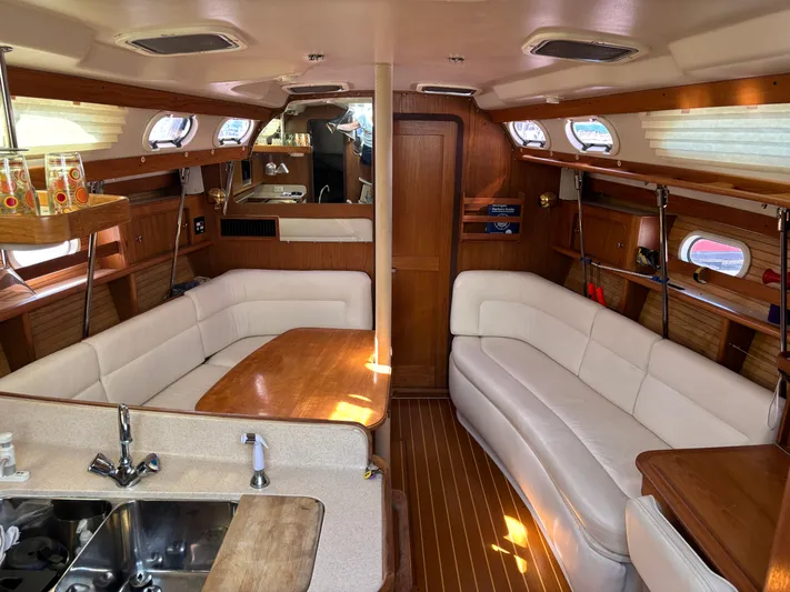 Renaissance Yacht Photos Pics Interior of 2000 Catalina 380 sailboat with white seating and wooden accents.