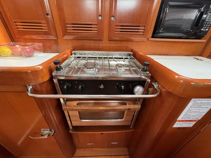  Yacht Photos Pics 2006 Beneteau 373 yacht kitchen with stove, oven, and wooden cabinetry.