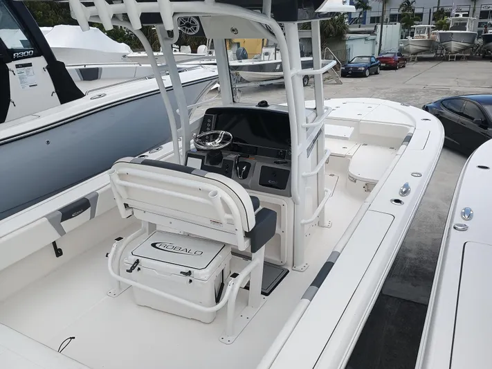 266-105 Yacht Photos Pics 2023 Robalo 266 Cayman SD boat interior with helm and seating, docked at marina.