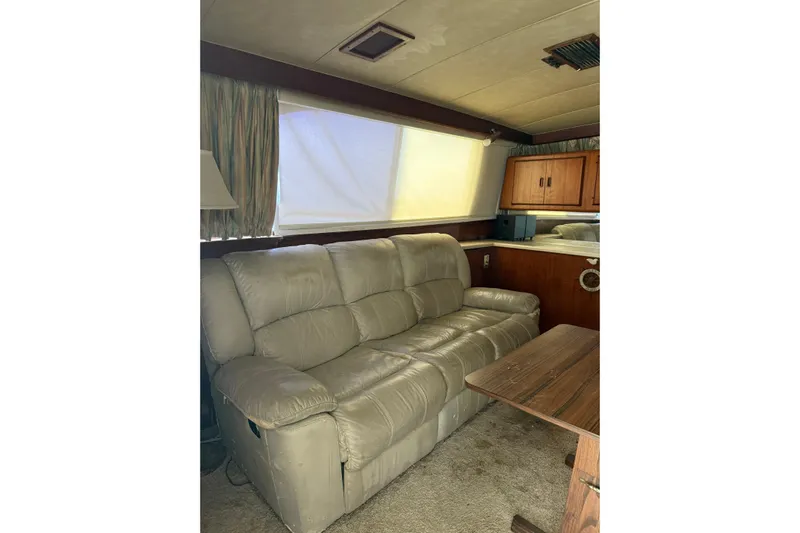 Marisabel Yacht Photos Pics Interior of 1984 Bertram 46 Convertible yacht with beige leather sofa and wooden cabinetry.
