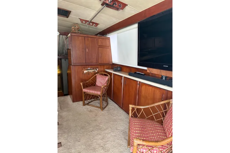 Marisabel Yacht Photos Pics 1984 Bertram 46 Convertible interior with wooden cabinets, chairs, and a large TV.