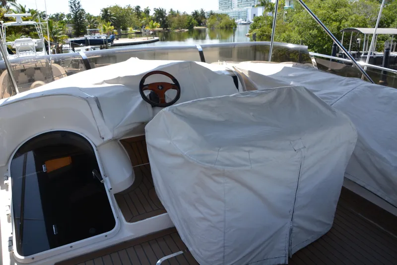 B&t Escape Yacht Photos Pics Covered helm area of a 2005 Princess 61 yacht, docked near lush greenery.