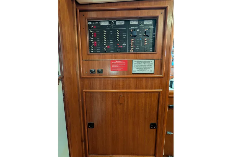 'mystic Cay' Yacht Photos Pics Electrical panel on a 2002 Hunter 450 Passage sailboat, featuring wooden cabinetry.