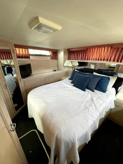  Yacht Photos Pics 1991 Hatteras 40 Motor Yacht bedroom with bed, TV, and red curtains.