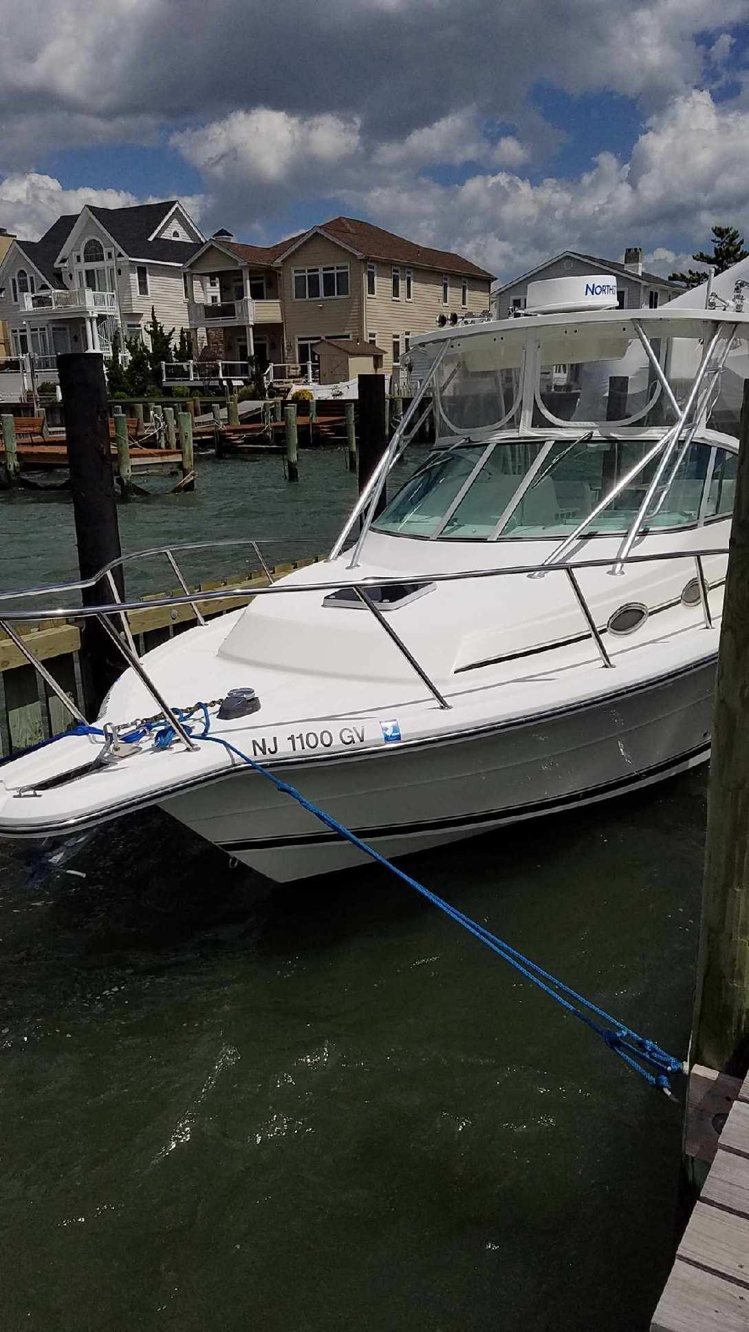 2004 Stamas 310 Express boat docked at a marina with waterfront homes in the background.