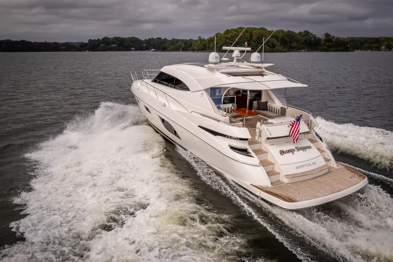 Change Happens Yacht Photos Pics 2017 Riviera 6000 Sport Yacht cruising on a lake under cloudy skies.