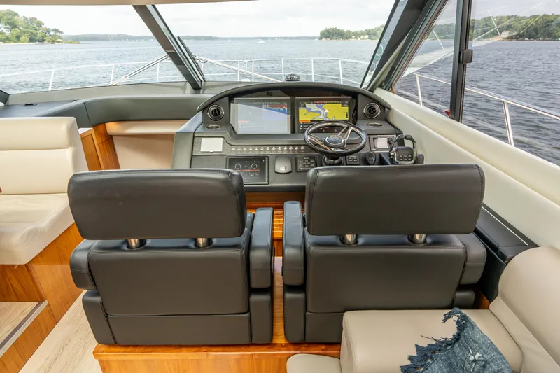 Change Happens Yacht Photos Pics Interior of 2017 Riviera 6000 Sport Yacht with dual black leather seats and navigation controls.