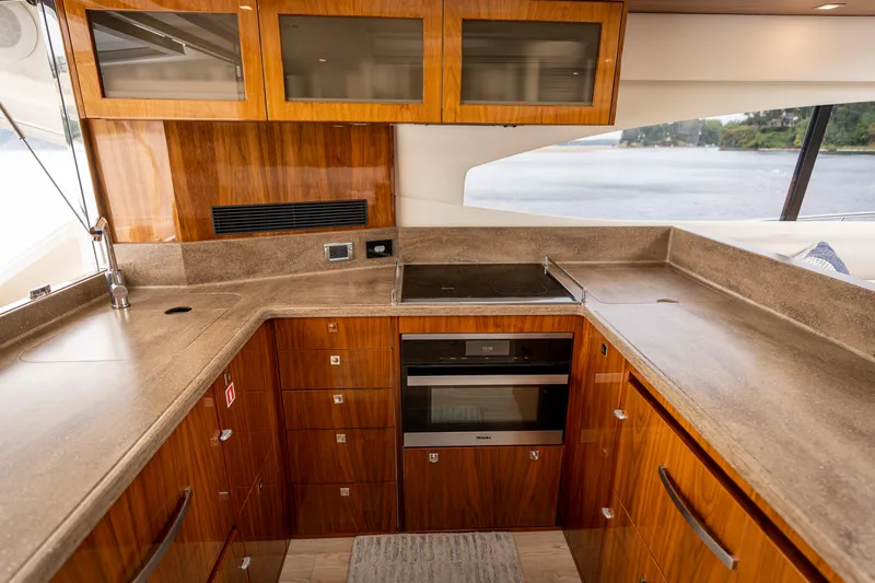 Change Happens Yacht Photos Pics Luxurious kitchen interior of 2017 Riviera 6000 Sport Yacht with wood cabinetry and modern appliances.