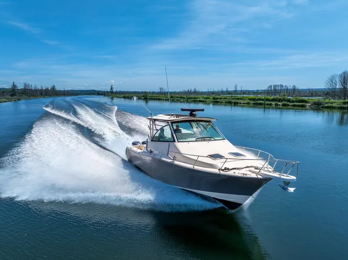  Yacht Photos Pics 2019 Grady-White Express boat cruising on a serene river under a clear blue sky.