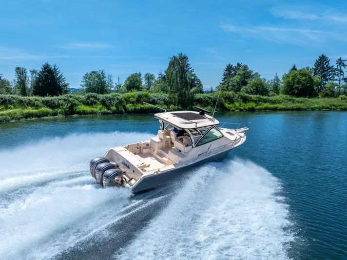  Yacht Photos Pics 2019 Grady-White Express boat cruising on a scenic river under a clear blue sky.