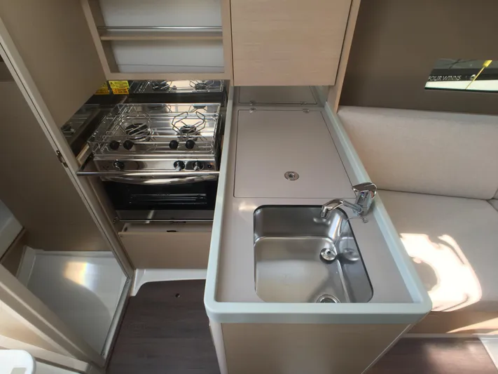  Yacht Photos Pics Modern kitchen in 2024 Beneteau Oceanis 30.1 yacht with stove, sink, and light wood cabinetry.