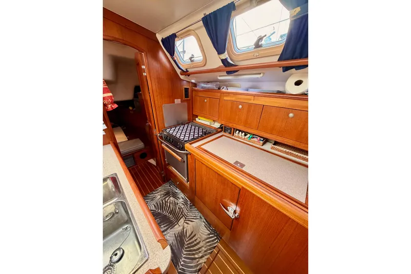 Serendipity II Yacht Photos Pics Interior of 2002 Hunter 460 sailboat, featuring a compact kitchen with wooden cabinetry and appliances.
