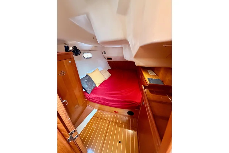 Serendipity II Yacht Photos Pics Cozy cabin interior of 2002 Hunter 460 sailboat with red bedding and wooden furnishings.