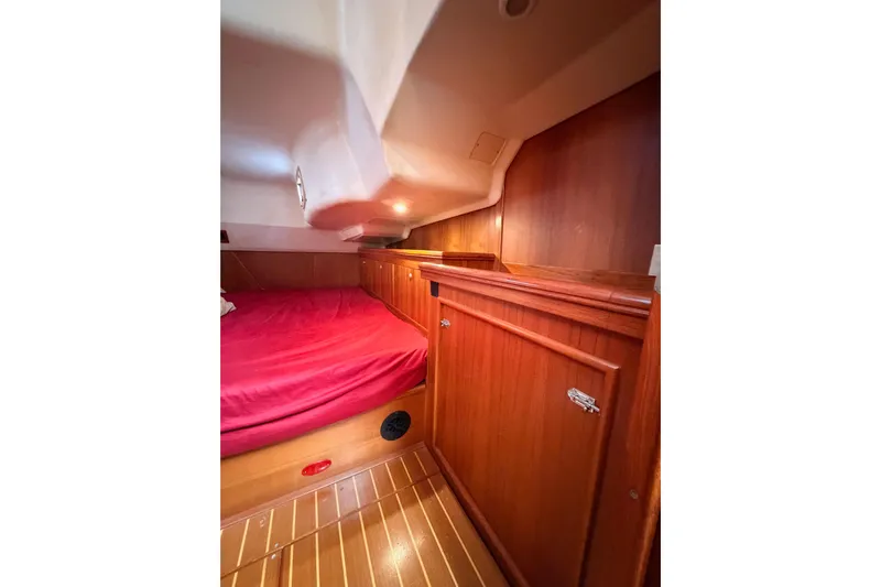 Serendipity II Yacht Photos Pics Interior cabin of 2002 Hunter 460 yacht with wooden cabinetry and red bedding.
