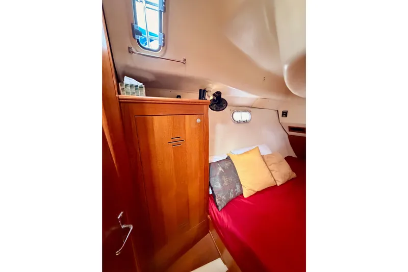 Serendipity II Yacht Photos Pics Cozy cabin interior of 2002 Hunter 460 sailboat with wooden cabinetry and red bedding.