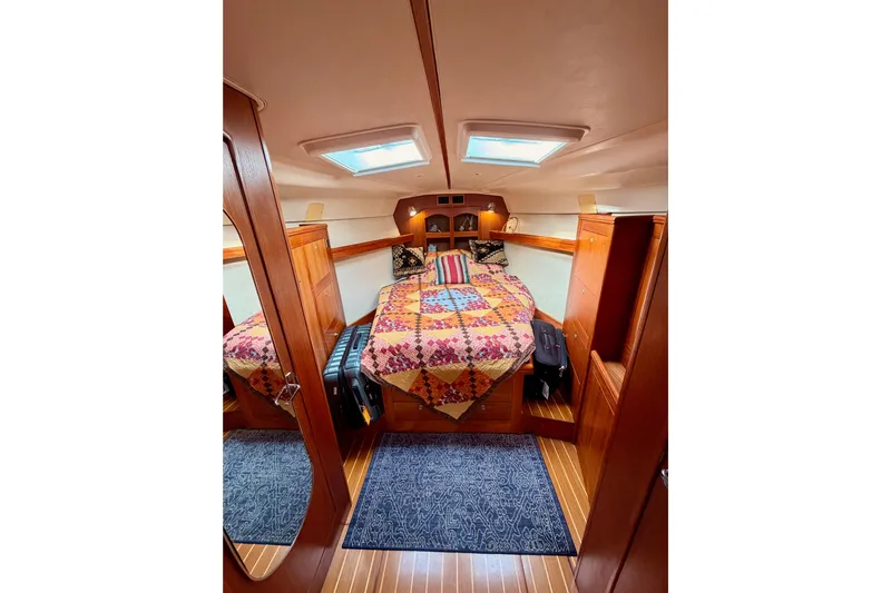Serendipity II Yacht Photos Pics Cozy cabin interior of 2002 Hunter 460 sailboat with colorful bedding and wooden finishes.
