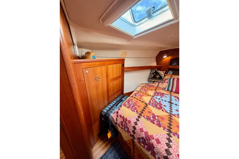 Serendipity II Yacht Photos Pics Cozy cabin interior of 2002 Hunter 460 yacht with colorful quilt and wooden cabinetry.