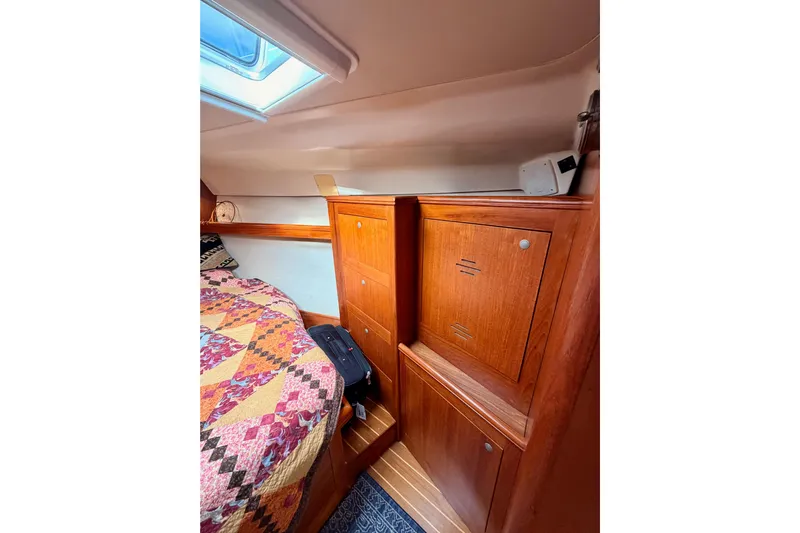 Serendipity II Yacht Photos Pics Interior of 2002 Hunter 460 sailboat with wooden cabinets and colorful quilted bed.