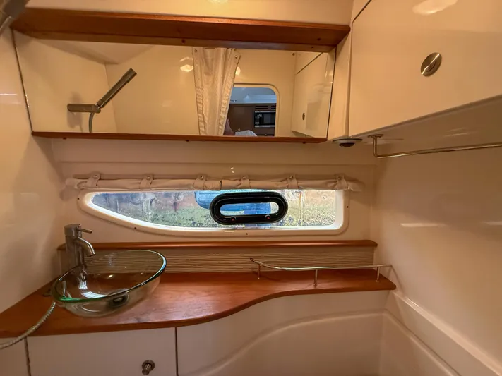 Yacht Photos Pics 2016 Sea Ray 350 Sundancer bathroom with glass sink, wooden accents, and porthole window.