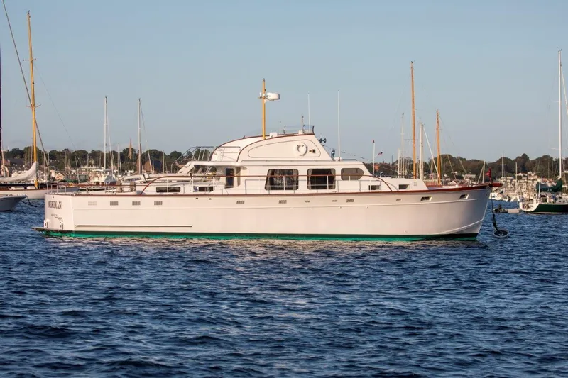 Huckins Yacht Corporation Yacht Photos Pics 1964 Huckins Out Islander 56 yacht on calm water, with marina background.