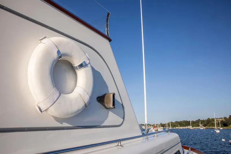 Huckins Yacht Corporation Yacht Photos Pics 1964 Huckins Out Islander 56 yacht with lifebuoy, docked in a serene harbor.