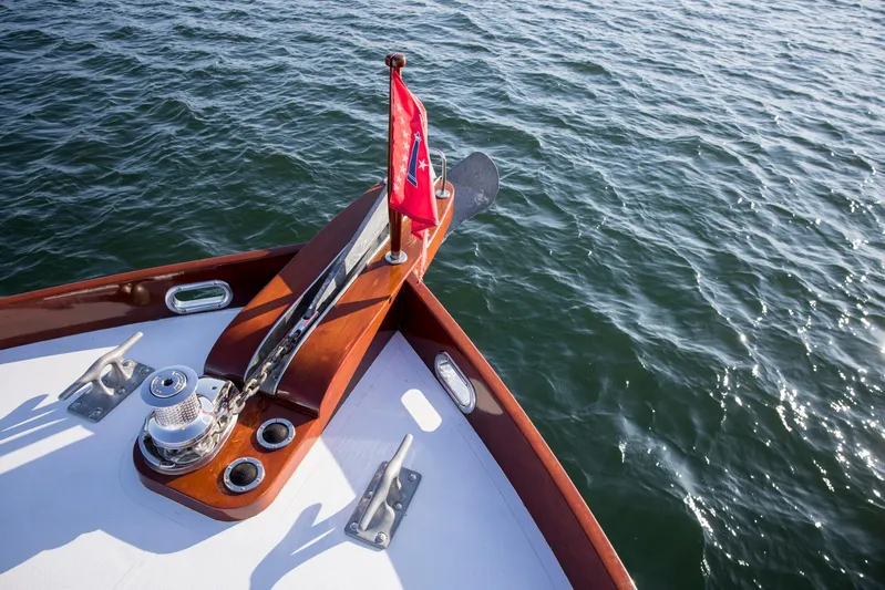 Huckins Yacht Corporation Yacht Photos Pics Bow of 1964 Huckins Out Islander 56 yacht with red flag on calm water.