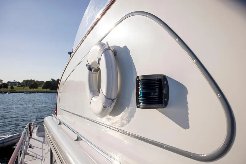 Huckins Yacht Corporation Yacht Photos Pics 1964 Huckins Out Islander 56 yacht with lifebuoy, docked by the water.