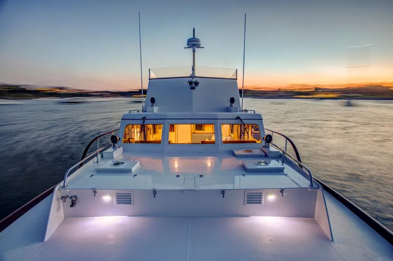 Huckins Yacht Corporation Yacht Photos Pics 1964 Huckins Out Islander 56 yacht cruising at sunset on calm waters.