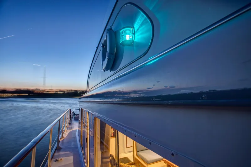 Huckins Yacht Corporation Yacht Photos Pics 1964 Huckins Out Islander 56 yacht at sunset, showcasing sleek design and illuminated interior.