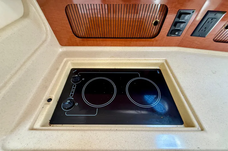  Yacht Photos Pics 2004 Sea Ray 320 Sundancer kitchen with built-in electric stove and wooden cabinetry.