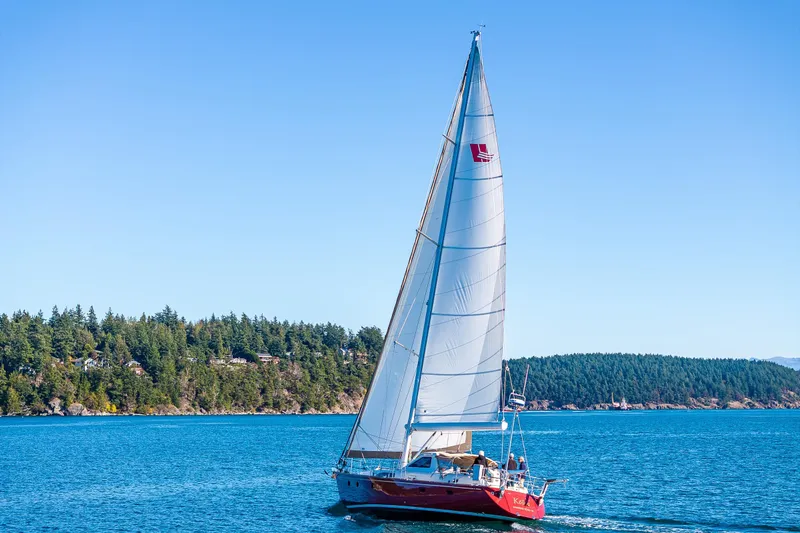 Kolea Yacht Photos Pics Sailing yacht Ron Holland 50, 2013 model, cruising on blue waters near a forested shoreline.