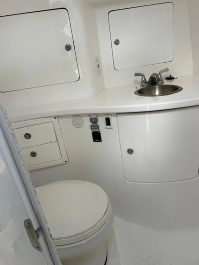 Overboard Yacht Photos Pics 2005 Intrepid 370 Cuddy boat bathroom with sink, toilet, and storage cabinets.