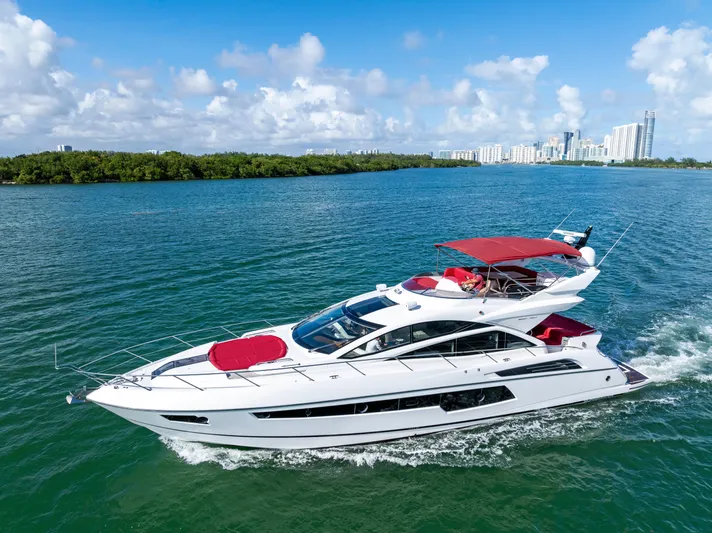 Gem Yacht Photos Pics 2014 Sunseeker 68 Sport Yacht cruising on blue water with city skyline in background.
