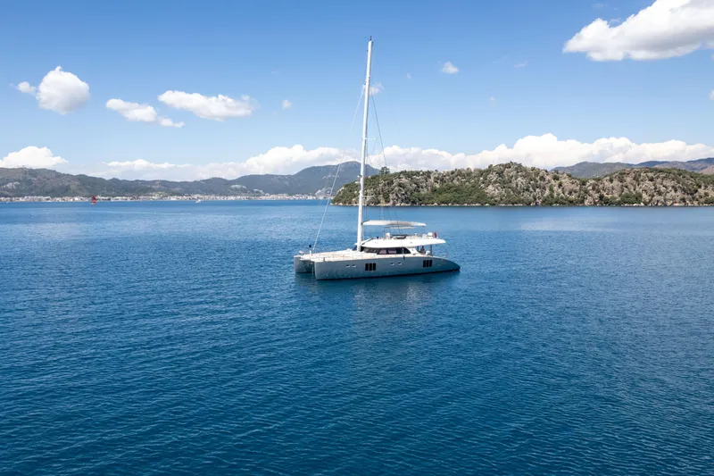 Seazen II Yacht Photos Pics Luxurious 2008 Sunreef 70 catamaran sailing in serene blue waters with scenic mountain backdrop.