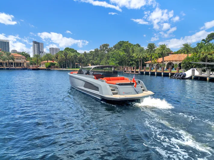 Vesper Yacht Photos Pics Vanquish Yachts VQ 54 cruising on a sunny day, surrounded by lush greenery and waterfront homes.