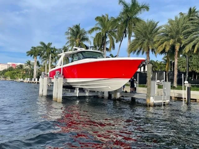 Feeling Knotty Yacht Photos Pics 2023 Tiara Yachts 48 LS in vibrant red, docked by palm trees.