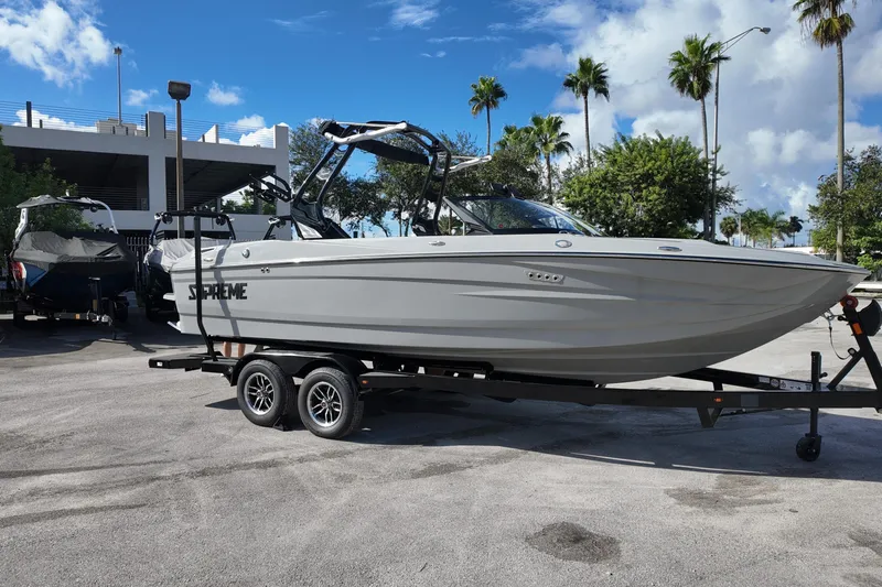  Yacht Photos Pics 2025 Supreme S220 boat on trailer, parked outdoors under a clear blue sky.